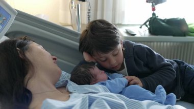 Yenidoğan 'ın İlk Günü Kardeşler tarafından karşılandı - Hastanedeki Otantik Aile Sahnesi, klinikte doğum sonrası annelik sahnesi, kardeşler arasında iç açıcı bir an.