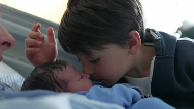 Küçük çocuk, doğumdan sonra ilk kez yeni doğan erkek kardeşiyle hastanede tanışıyor. Çocuk, bebekle Eskimo öpücüğü veriyor. Gerçek aile bağlarını kuvvetlendiriyor.