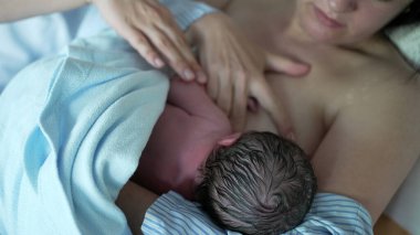Anne, yeni doğan bebeği ilk kez hastane kliniğinde emziriyor. Gerçek hayatta anne bebeğini ilk dakikalarda, anne bakımında ve büyümesinde besliyor.