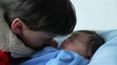 Ağabey ve yeni doğan bebek arasındaki hassas etkileşim, yakın aile ortamında kardeş bağının ve nazik bakımın altını çizmek. Yakalanmış aşk ve sıcaklık anları