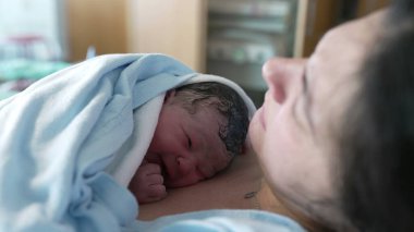 Doğumdan hemen sonra hastanedeki klinikte annesinin göğsünde ağlayan yeni doğmuş bir bebeğin dünyaya geldiği gerçek hayatta gerçek doğum sahnesi.
