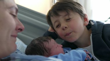 Küçük çocuk, doğumdan sonra ilk kez yeni doğan erkek kardeşiyle hastanede tanışıyor. Çocuk, bebekle Eskimo öpücüğü veriyor. Gerçek aile bağlarını kuvvetlendiriyor.