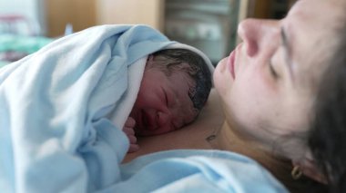 Doğumdan hemen sonra hastanedeki klinikte annesinin göğsünde ağlayan yeni doğmuş bir bebeğin dünyaya geldiği gerçek hayatta gerçek doğum sahnesi.