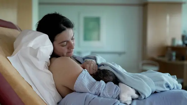 stock image New mother bonding moment with her newborn baby at hospital after giving birth, breastfeeding infant child in post-birth at clinic