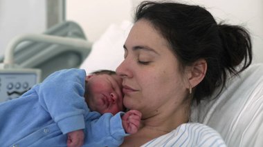 Anne ve yeni doğan bebek doğumdan sonra hastanede. Otantik gerçek hayat. Yeni anne bebeğini kucağında tutuyor.