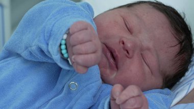 Doğumdan hemen sonra hastanedeki hayatın ilk günlerinde bebeğin sevimli yakın plan yüzü. Anne eli, alnını okşayarak bebek bakımı, annelik ve annelik kavramına bağlanıyor.