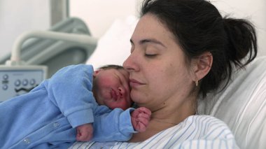 Anne ve yeni doğan bebek doğumdan sonra hastanede. Otantik gerçek hayat. Yeni anne bebeğini kucağında tutuyor.