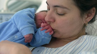 Anne, yeni doğmuş bir bebeğin ilk saatlerinde elini öpüyor. Anne ve bebek için iç açıcı bir an, annelik ve annelik kavramı.