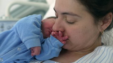 Anne, yeni doğmuş bir bebeğin ilk saatlerinde elini öpüyor. Anne ve bebek için iç açıcı bir an, annelik ve annelik kavramı.