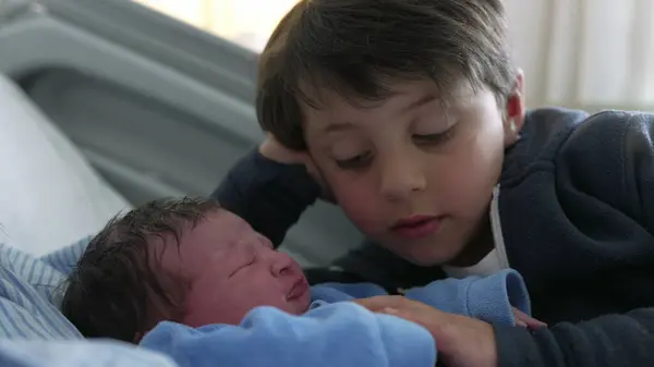 stock image Young boy watching his newborn baby brother at hospital after birth, authentic real life siblings meeting for the first time, day one of infant being welcomed by family at clinic