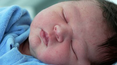 Huzur içinde uyuyan yeni doğmuş bir bebeğin huzur dolu bir anında yeni hayatın narin özelliklerini ve saf masumiyetini yakalıyor.