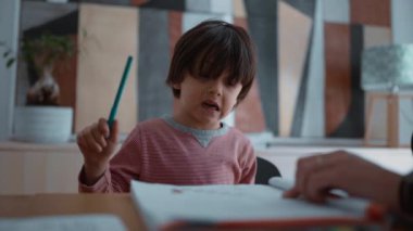 Öğrenme konusunda isteksiz ve zorlanan bir çocuk, öğrenme faaliyetleri sırasında hayal kırıklığı ve zorluk göstererek, destekleyici bir ev ortamında eğitimin zorluklarını vurgulayarak