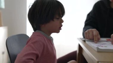 Anne babasıyla birlikte eğitim faaliyetlerinde azimli bir çocuk, evde öğrenim ortamında ebeveynlerin rol almasının ve kararlılığın destekleyici rolünü vurguluyor