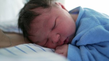 Yeni doğmuş bir bebeğin mavi bir battaniyeye sarılıp anne-baba ve çocuk arasındaki samimiyet ve bağın resmedildiği bir bebeğin yakın çekimi. Yeni doğan bakımı ve aile teması için ideal
