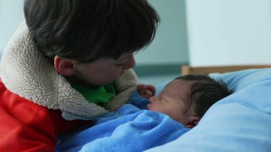 Big brother gently bonding with newborn baby, showcasing love and care in an intimate family moment. Highlights the warmth and connection between siblings