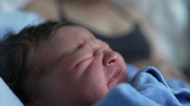 Yeni doğan bebek ağlamasına yakın çekim, mavi battaniyeye sarılı, ham duyguları ve hayatın ilk ifadelerini yakalamak, bebeklik, incinebilirlik ve yeni başlangıçların güzelliği için idealdir.