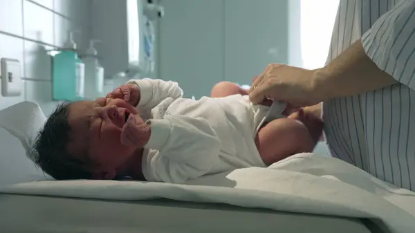 stock image Newborn baby being dressed in a white outfit by a parent, lying on a hospital changing table, highlighting the nurturing care given to infants in a medical setting right after birth