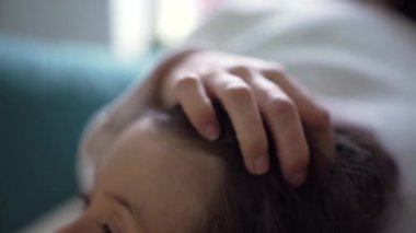 Çocuğun kafasının yakın çekimi, ebeveynin eliyle çocuğun saçlarını okşaması, bir anlık ilgi, şefkat ve rahatlık göstermesi, ebeveynler ve çocuklar arasındaki bağı vurgulaması,