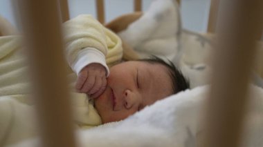 Sarı tulumlu sevimli bir bebek tahta bir beşikte huzur içinde uyuyor. Erken çocukluğun sükunetini ve saflığını yakalıyor. Aile ve sağlık hizmetleri için ideal.