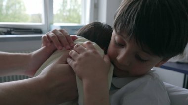 Büyük kardeş, yeni doğmuş bebeği sarılar içinde şefkatle kucaklıyor ve rahatlatıyor. Aile hayatının ilk günlerinde kardeşler arasındaki sevgi dolu bağı ve nazik etkileşimi vurguluyor.