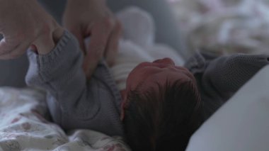 Yeni doğan ebeveynler rahat gri bir kazak giyip bebeklere sunulan hassas bakım ve sıcaklığa odaklanarak yeni doğanları rahat ve korunmuş tutmanın önemini vurguluyorlar.