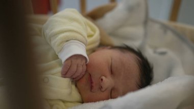 Yeni doğan bebek, sarı tulumlu bir beşikte huzur içinde uyuyor. Huzurlu bir dinlenme ve masumiyet anı yakalıyor. Aile, ebeveynlik ve sağlık konuları için birebir.