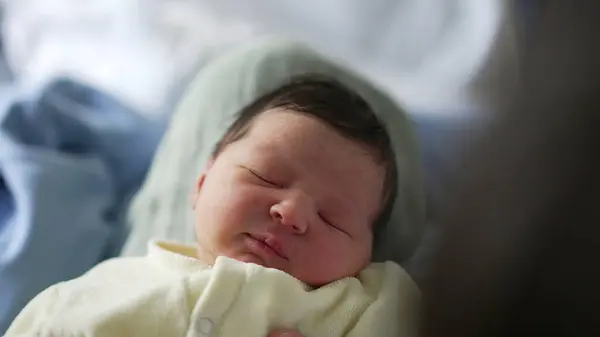 Stock image Newborn baby with a slight smile, sleeping contentedly in a soft blanket. serene and peaceful expression highlights the innocence and purity of a newborn