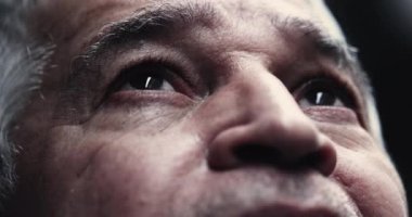 Yukarı bakan gri saçlı yaşlı bir adam, yüzü umut ve yansıma ile aydınlanmış, kırışıklıklar ve yaş noktaları görünür, bilgeliği, deneyimi sembolize eden, ve derin düşüncelere dalmış