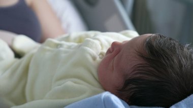 Yeni doğan bir bebeğin huzur içinde dinlenmesi, Yumuşak Özellikler ve Kapalı Kapalı Hastane Ortamı 'ndaki Koyu Saçlar