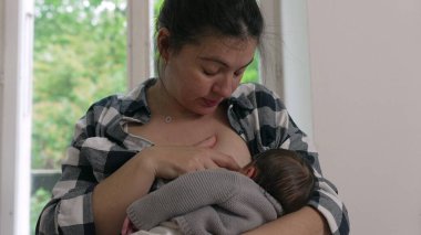 Anne yeni doğmuş bebeğini parlak, rahat bir odada emzirerek bir analık sevgi ve ilgi anı yakalıyor. Bebek beslenme sırasında annesinin kollarında huzur içinde yatar. 