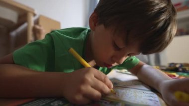 Konforlu ev ortamında, yeşil tişörtlü, odaklanmış ifade, doğal ışık, eğitici ve yaratıcı oyun, kapalı mekanda,