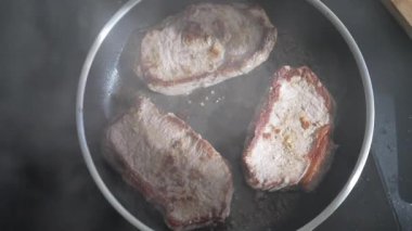 Tavada kızaran üç domuz pirzolasının yakın çekimi sulu dokusunu ve altın-kahverengi kabuğunu gösteriyor yemek tutkunları ve ağız sulandıran görseller arayan mutfak sunumları için mükemmel.