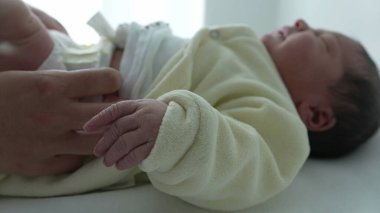 Hemşire hastane rutini sırasında altını değiştirirken yeni doğan bebekler ellerini uzatıyor. Yeni doğan bebekler için hassas bakım ve bakım gereksinimleri, ilk günlerde nazik bakımın önemini vurgulamak 
