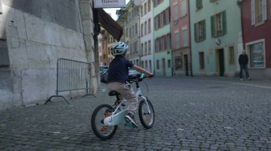 Tarihi kentsel alandaki dar kaldırım taşı caddelerinde bisiklet süren bisikletli çocuk, keşif ve aktif oyun, seyahat, yaşam tarzı ve güvenlik temaları için mükemmel