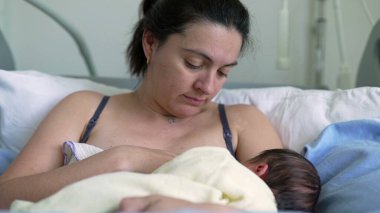 Anne yeni doğan bebeği hastane yatağında emziriyor, anne bakımını gösteriyor, büyütüyor ve anne ile bebek arasında sakin bir hastane ortamında samimi bir bağ kuruluyor.