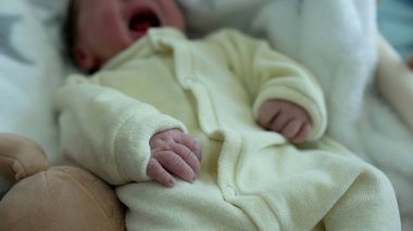 Bebek beşikte dinleniyor, yumuşak, beyaz bir battaniyeyle örtülmüş, hafifçe hareket ediyor, çocukluklarının sükunetini ve konforunu gösteriyor, ve yeni doğanlara ilk günlerinde verilen hassas bakımı gösteriyor.