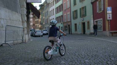 Tarihi kentsel alandaki dar kaldırım taşı caddelerinde bisiklet süren bisikletli çocuk, keşif ve aktif oyun, seyahat, yaşam tarzı ve güvenlik temaları için mükemmel