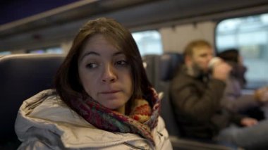 Trendeki endişeli kadın, tren raylar boyunca ilerlerken derin düşüncelere dalıyor. Cebinden bir hap alır ve onu alır.