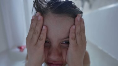 Küvette gözleri kapalı bir çocuk, saf duygu ve samimi ifade sergiliyor, çocukluk ruh hallerini ve anlarını tasvir etmek için mükemmel, yaşam tarzı, ebeveynlik ve zihinsel sağlık tasvirleri için ideal.