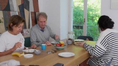 Aile kahvaltıdan keyif alıyor. Huzurlu ve rahat bir ev ortamında çok nesilli bağların sıcaklığını ve bağlantısını yakalıyor.