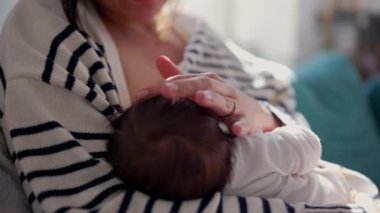 Anne sevecen bir şekilde yeni doğmuş bebeği güneş ışığıyla kucaklıyor, samimi ve huzurlu bir ev ortamında bağ kurma anını sergiliyor.