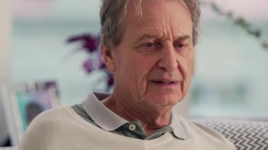 Kanepede otururken kızgın numarası yapan yaşlı bir adam neşeli ve esprili bir an sergiliyor. Bu onun hayat dolu kişiliğini ve ruhunu vurguluyor.