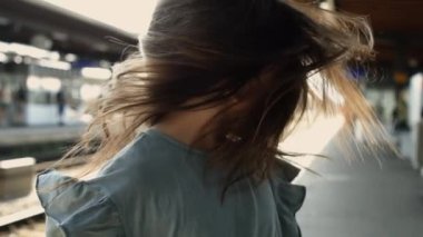 Kızın saçı tren istasyonunda uçuşuyor, 1000 fp yavaş çekim, dinamik hareket, dramatik etki, açık hava sahnesi, enerjik an, neşeli aktivite