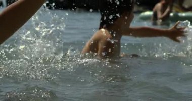 Çocuk gölde yüzüyor, 800 fps hızla ağır çekimde, neşeli ve neşeli, yaz eğlencesi, su sıçramaları, açık hava macerası