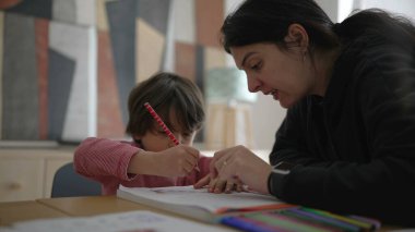 Çocuğa okul ödevlerinde yakından yardımcı olan ebeveyn, detaylı rehberlik ve bakım evi ortamında odaklanmış öğrenme, kendini adamışlık ve destek gösterme