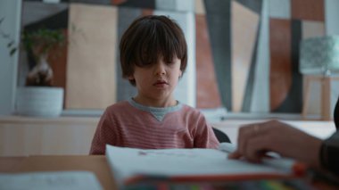 Öğrenme konusunda isteksiz ve zorlanan bir çocuk, öğrenme faaliyetleri sırasında hayal kırıklığı ve zorluk göstererek, destekleyici bir ev ortamında eğitimin zorluklarını vurgulayarak