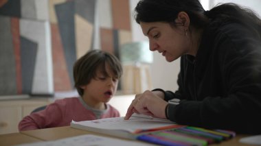 Çocuğa okul ödevlerinde yakından yardımcı olan ebeveyn, detaylı rehberlik ve bakım evi ortamında odaklanmış öğrenme, kendini adamışlık ve destek gösterme