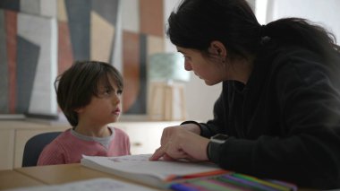 Çocuğa okul ödevlerinde yakından yardımcı olan ebeveyn, detaylı rehberlik ve bakım evi ortamında odaklanmış öğrenme, kendini adamışlık ve destek gösterme