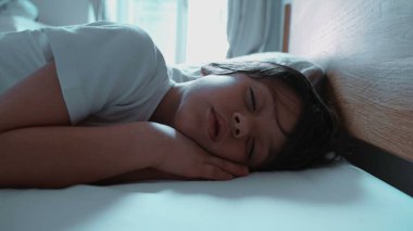 Rahat bir yatakta derin bir uykuda olan çocuk, huzurlu bir uykunun sükunetini ve güvenliğini sergiliyor, yumuşak sabah ışığı huzurlu atmosfere ekliyor.