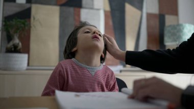 Bir öğrenme etkinliği sırasında yorgun bir çocuğu nazikçe teselli etmek, eğitimin besleyici yönünü ve bir ev ortamında ebeveynler ve çocuklar arasındaki bağı göstermektedir.